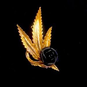 Gold tone, costume jewelry leaf with a black rose brooch